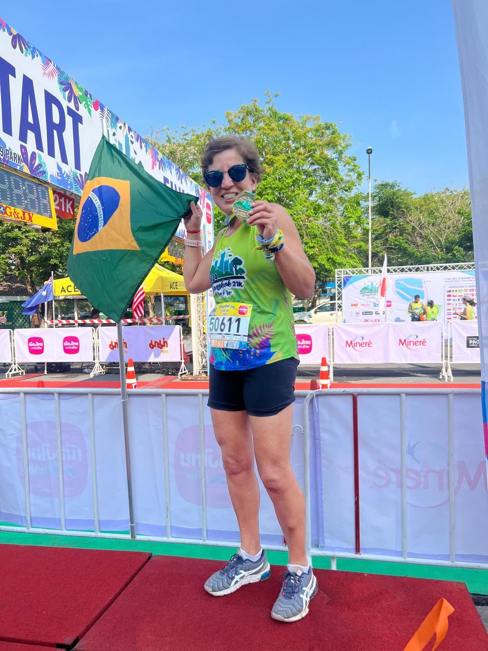 Graça com a medalha do Bangkok 21K e a bandeira do Brasil